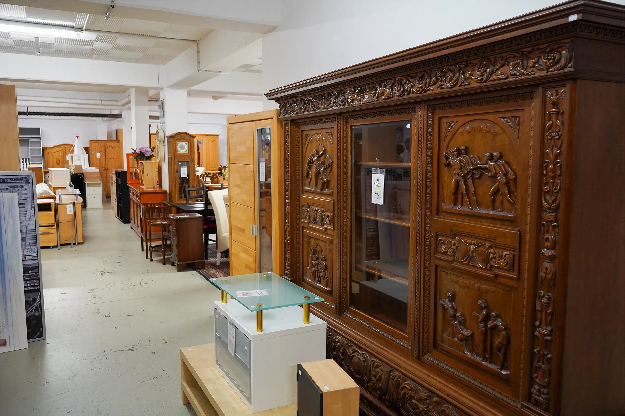 Gebrauchte Möbel in einem Laden, darunter ein großes geschnitztes Holzschrank-Unikat.